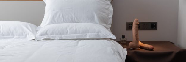 anal dildo Suction cup dildo placed on nightstand next to white bed