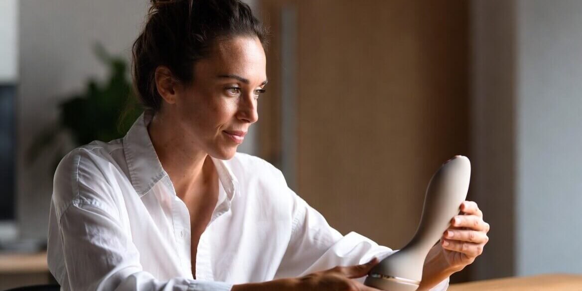 Sexual wellness professional examining a minimalist body-safe product prototype, representing the bridge from therapist insights to manufacturable sexual wellness products