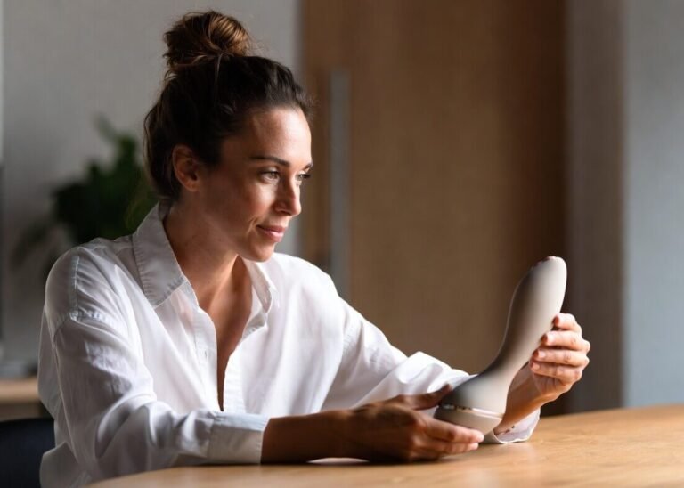 Sexual wellness professional examining a minimalist body-safe product prototype, representing the bridge from therapist insights to manufacturable sexual wellness products