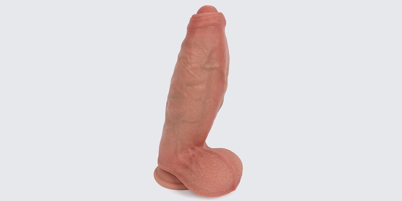 Realistic dual-density silicone dildo with lifelike skin texture, defined head, and suction-cup base on a light gray background