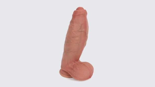 Realistic dual-density silicone dildo with lifelike skin texture, defined head, and suction-cup base on a light gray background