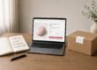 Notebook with a 90-day plan, a laptop showing a Shopify product page, and a discreet shipping box on a desk.